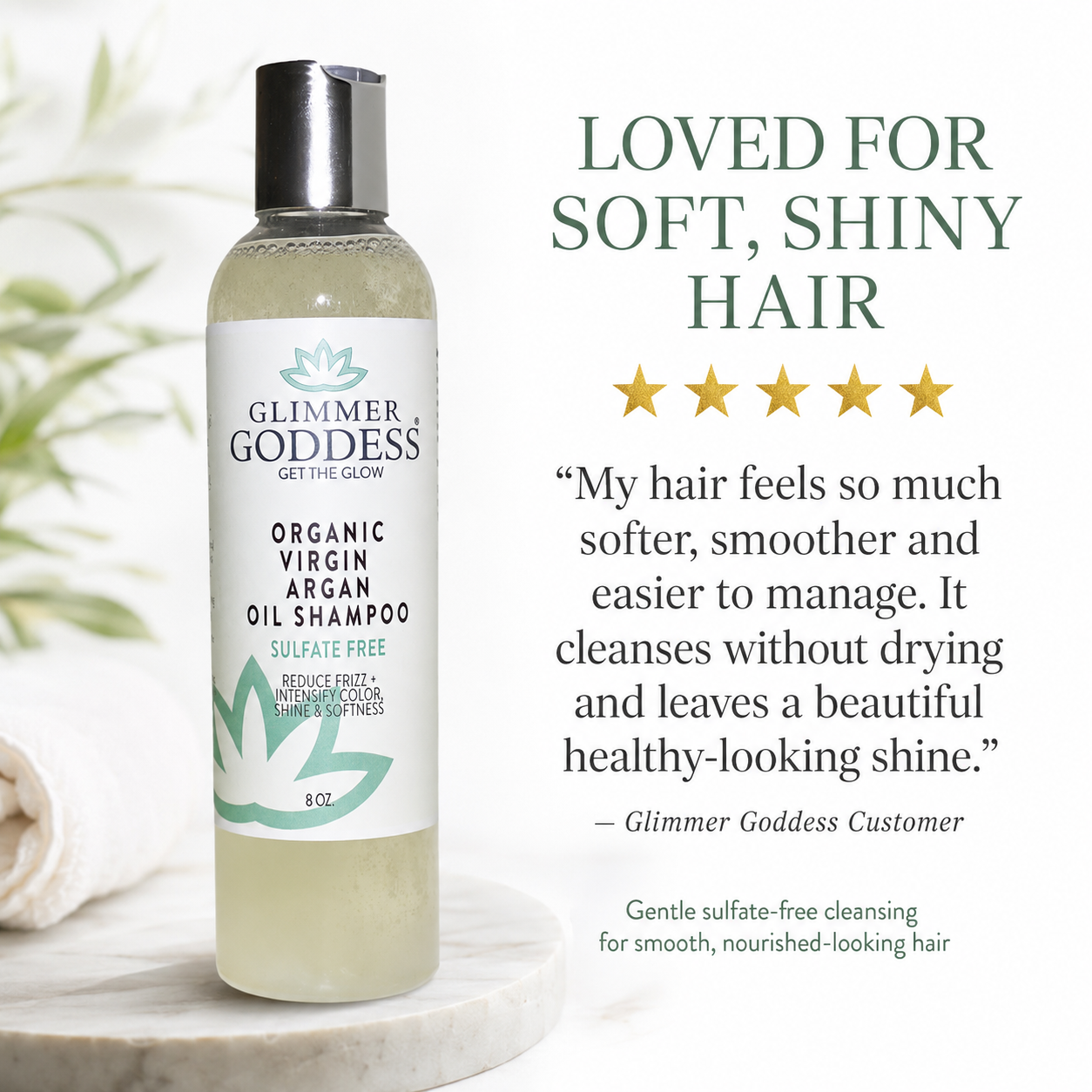 Glimmer Goddess Organic Virgin Argan Oil Shampoo bottle displayed on a marble surface next to a rolled towel, with promotional text on the right reading 'LOVED FOR SOFT, SHINY HAIR' and a customer quote.