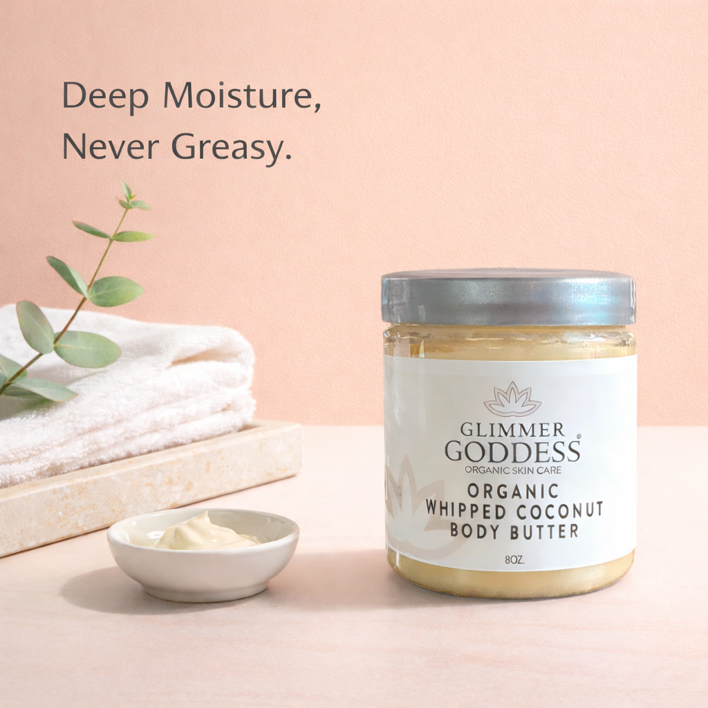 Glimmer Goddess® Organic Whipped Coconut Body Butter (8 oz) jar on a solid peach background in a minimal bathroom vanity scene with a white towel and small cream smear, showing a clean, luxury skincare lifestyle look.