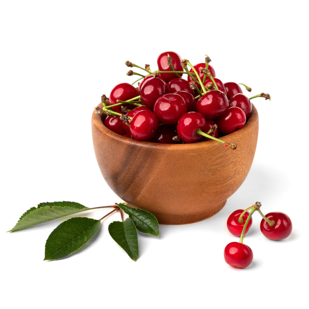 Fresh red cherries in a wooden bowl with green leaves on a white background