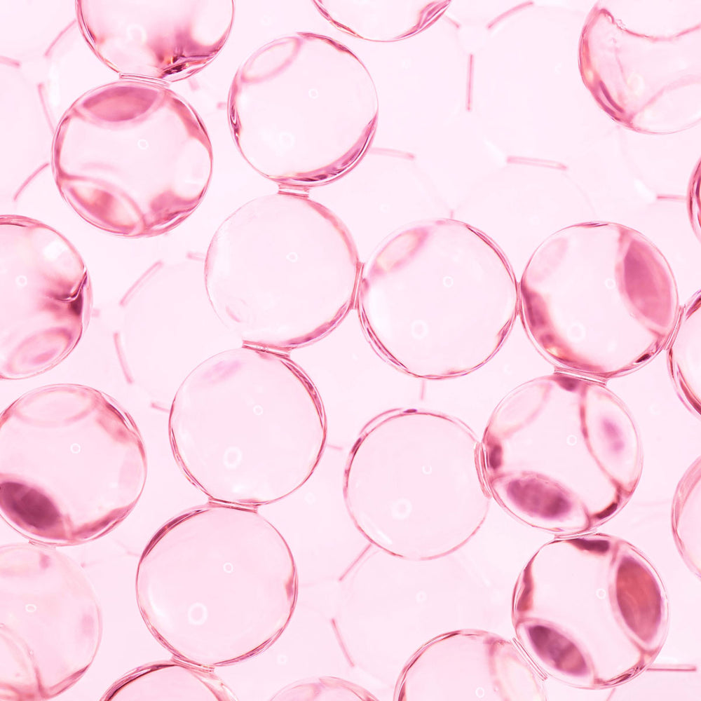 close-up of pink transparent peptide spheres, skincare ingredient macro