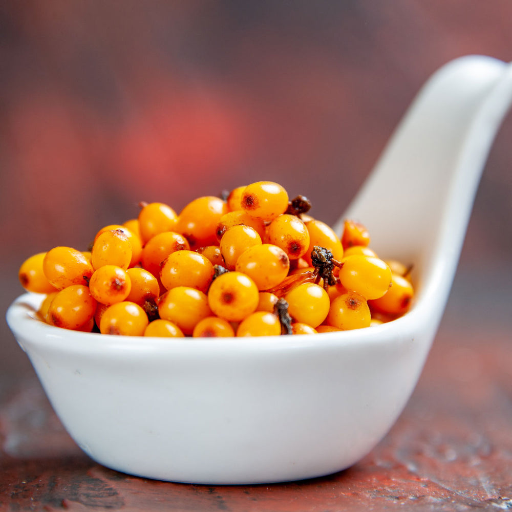 Fresh sea buckthorn berries in a white dish, vibrant orange superfood for skincare